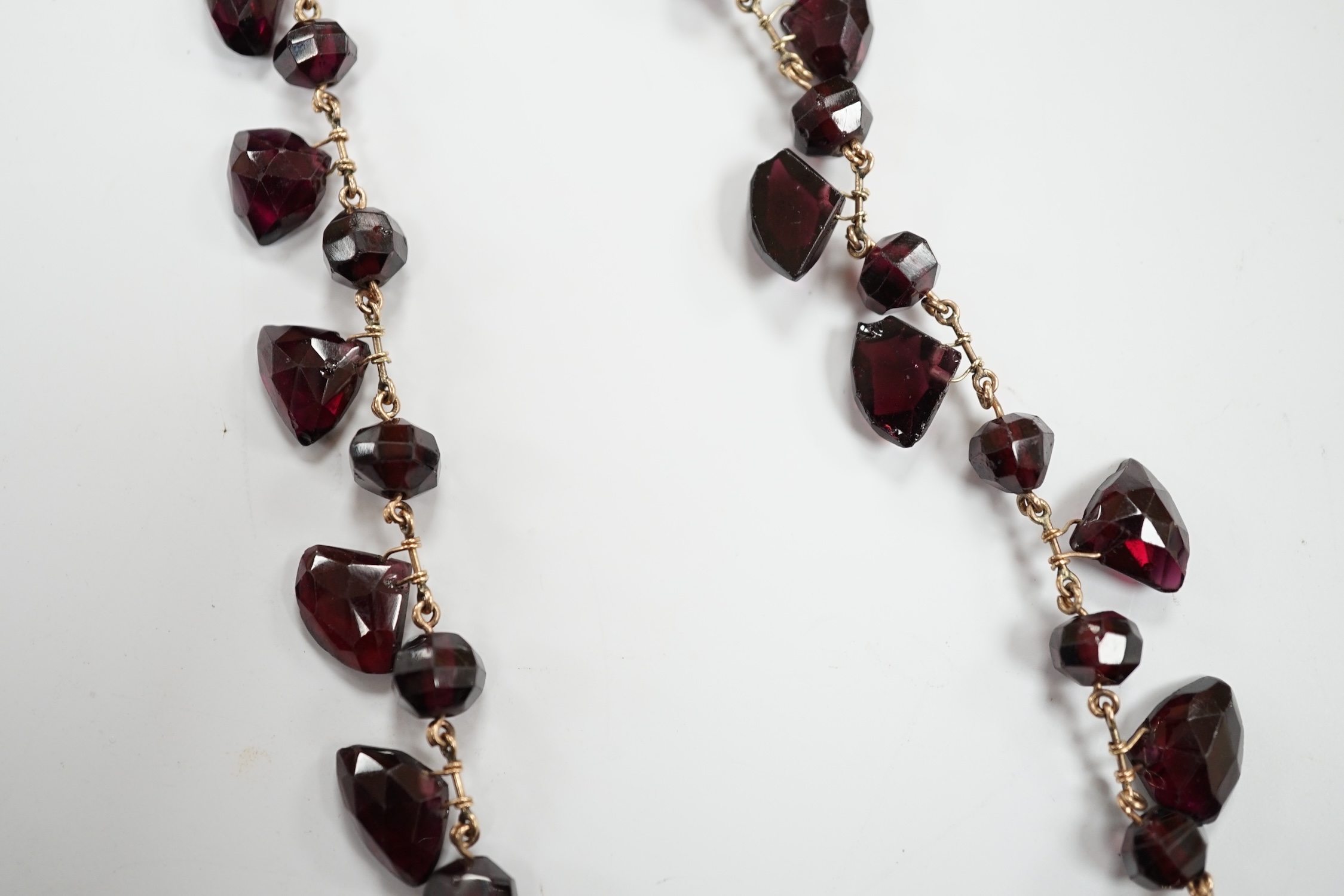 A Victorian yellow metal (test as 9ct) and garnet drop fringe necklace, set with faceted circular and pebble cut stones, 38cm, gross weight 32.6 grams.